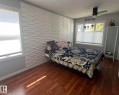 Room featuring a textured accent wall, wood-finish flooring, and a ceiling fan - 5027 49 Ave, Vilna, AB  - Indoor Photo Showing Bedroom 