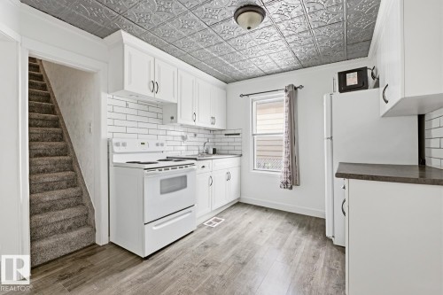 The kitchen features white cabinetry, white subway tile backsplash, and a tin-style ceiling - 10927 93 Street Nw, Edmonton, AB - Indoor Photo Showing Kitchen