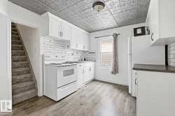 The kitchen features white cabinetry, white subway tile backsplash, and a tin-style ceiling - 