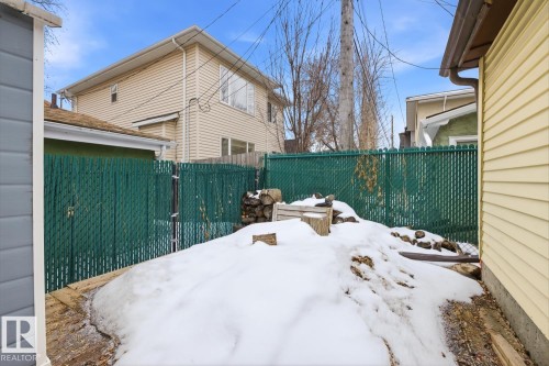 The property includes a green fence and a side yard with varied terrain - 10927 93 Street Nw, Edmonton, AB - Outdoor