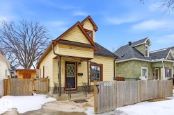 The property features light-colored siding, a dark roof, and a wooden fence along the front - 