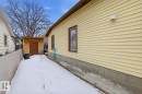 The property features a yellow siding exterior with brown window trim and a visible foundation - 10927 93 Street Nw, Edmonton, AB  - Outdoor With Exterior 