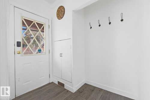 Entryway featuring a white door with a diamond-patterned glass insert, a built-in storage cabinet, and dark-toned flooring - 10927 93 Street Nw, Edmonton, AB - Indoor Photo Showing Other Room