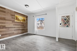 The room features wood plank flooring, a decorative accent wall with horizontal wood planks, and a white door with a diamond-patterned window - 