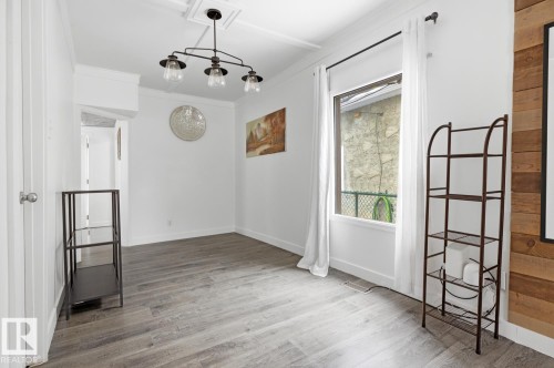 This bright room features wide plank flooring, a window with white curtains, and a ceiling light fixture - 10927 93 Street Nw, Edmonton, AB - Indoor Photo Showing Other Room