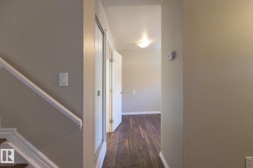 Inviting interior hallway with wood-finish flooring, light neutral wall paint, and white baseboards - 8039 27 Avenue, Edmonton, AB - Indoor Photo Showing Other Room