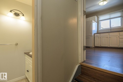Kitchen with wood-finish flooring, white cabinetry, a single basin sink, and window with blinds - 8039 27 Avenue, Edmonton, AB - Indoor