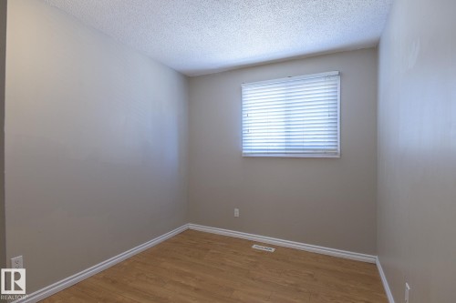 Spacious room with light-toned walls, wood-finish flooring, and white baseboards - 8039 27 Avenue, Edmonton, AB - Indoor Photo Showing Other Room