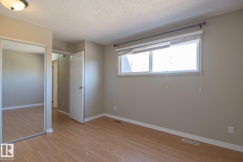 Room featuring wood-finish flooring, a double window, and a mirrored closet door - 8039 27 Avenue, Edmonton, AB - Indoor Photo Showing Other Room