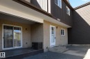 Ground-level patio with sliding glass doors, textured stucco exterior, and a secondary entry door - 8039 27 Avenue, Edmonton, AB  - Outdoor With Exterior 
