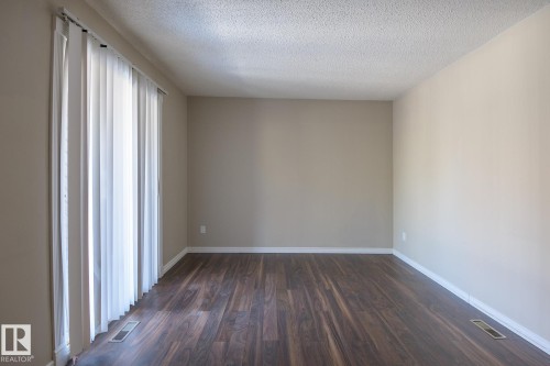 Room featuring wood-finish flooring, neutral wall tones, and white baseboards - 8039 27 Avenue, Edmonton, AB - Indoor Photo Showing Other Room