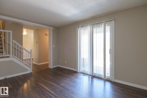 Spacious room featuring wood-finish flooring, neutral-toned walls, and white trim - 8039 27 Avenue, Edmonton, AB - Indoor Photo Showing Other Room