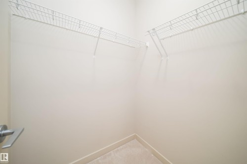 Walk-in closet featuring light-toned walls, wire shelving, and carpeting - 421 4008 Savaryn Drive, Edmonton, AB - Indoor With Storage