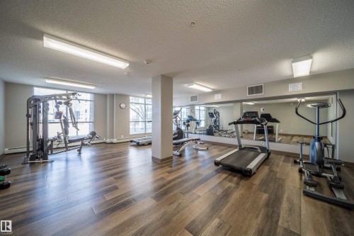 Fitness center featuring wood-finish flooring, a full-wall mirror, and ample natural light from multiple windows - 421 4008 Savaryn Drive, Edmonton, AB - Indoor Photo Showing Gym Room