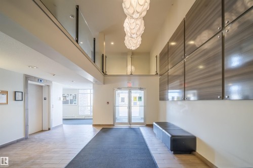 Lobby area featuring large format tile flooring, three decorative pendant light fixtures, and a glass-paneled upper-level railing - 421 4008 Savaryn Drive, Edmonton, AB - Indoor Photo Showing Other Room