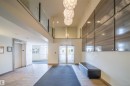Lobby area featuring large format tile flooring, three decorative pendant light fixtures, and a glass-paneled upper-level railing - 421 4008 Savaryn Drive, Edmonton, AB  - Indoor Photo Showing Other Room 