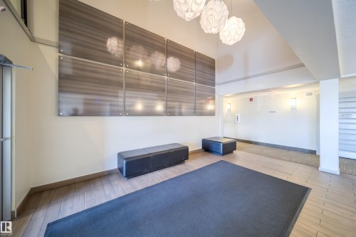 Building lobby featuring a paneled accent wall, contemporary pendant lighting, and wood-finish flooring - 421 4008 Savaryn Drive, Edmonton, AB - Indoor Photo Showing Other Room