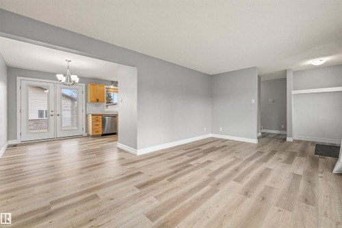 Spacious open-concept living area featuring light wood-finish flooring and neutral gray walls - 7927 71 Avenue, Edmonton, AB - Indoor