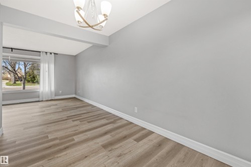 Spacious room featuring wood-finish flooring, light gray wall paint, and white baseboards - 7927 71 Avenue, Edmonton, AB - Indoor Photo Showing Other Room