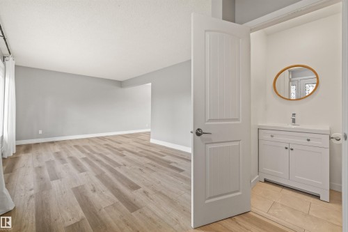 Spacious interior with wood-finish flooring and light gray painted walls - 7927 71 Avenue, Edmonton, AB - Indoor Photo Showing Other Room