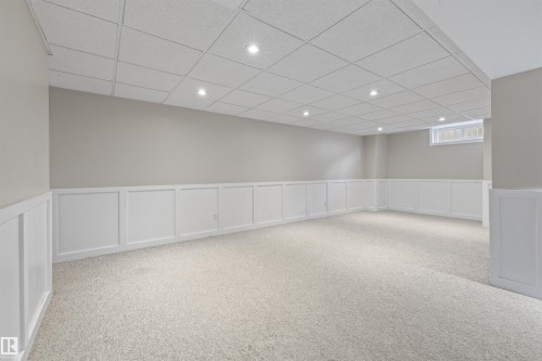 Spacious room featuring light-toned carpeting, wainscoting, and recessed lighting - 7927 71 Avenue, Edmonton, AB - Indoor
