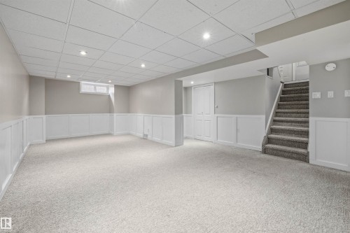 Finished lower-level room featuring light gray carpeting and white wainscoting - 7927 71 Avenue, Edmonton, AB - Indoor