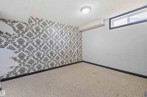 Room featuring a wall with black and white damask wallpaper, a single window, and light-colored carpet flooring - 7927 71 Avenue, Edmonton, AB - Indoor Photo Showing Other Room