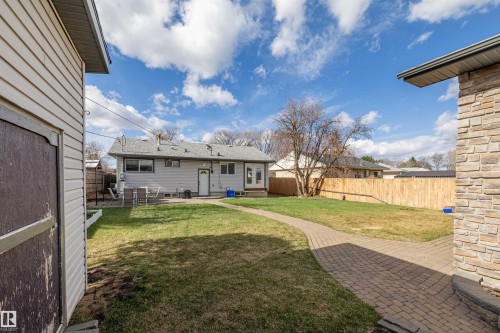 Expansive backyard featuring a manicured lawn, a paver pathway, and a new wood fence - 7927 71 Avenue, Edmonton, AB - Outdoor With Exterior