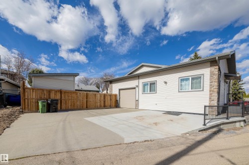 Exterior featuring neutral vinyl siding, stone accent details, and a concrete driveway - 7927 71 Avenue, Edmonton, AB - Outdoor