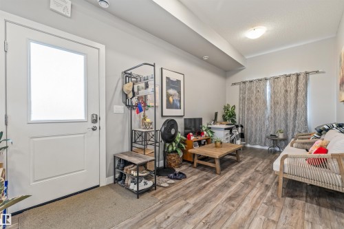 Light-filled entryway and living space featuring a white door with frosted glass panel, wood-finish flooring, recessed ceiling lighting, and neutral wall tones - 7927 71 Avenue, Edmonton, AB - Indoor Photo Showing Other Room
