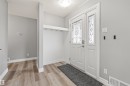 Entryway featuring a white main door with decorative glass inserts, wood-finish flooring, light gray wall paint, a built-in white shelf with hooks, and white trim throughout - 7927 71 Avenue, Edmonton, AB  - Indoor Photo Showing Other Room 