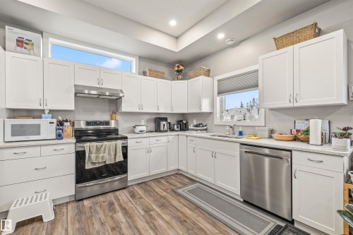 Kitchen featuring white shaker-style cabinetry, quartz countertops, and stainless steel appliances - 7927 71 Avenue, Edmonton, AB - Indoor Photo Showing Kitchen