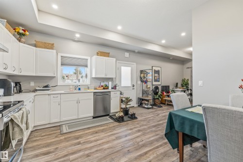 Kitchen featuring white cabinetry, light countertops, and wood-finish flooring - 7927 71 Avenue, Edmonton, AB - Indoor Photo Showing Kitchen