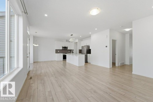 Open-concept living area featuring wood-finish flooring, white walls, and recessed lighting - 2011 207 Street, Edmonton, AB - Indoor Photo Showing Kitchen