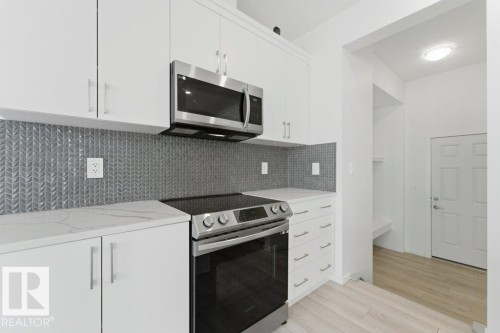 Modern kitchen featuring white cabinetry, a stainless steel range, and a coordinating stainless steel microwave - 2011 207 Street, Edmonton, AB - Indoor Photo Showing Kitchen