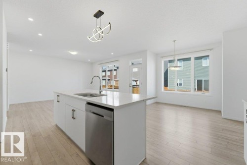 Open-concept living area featuring light wood-finish flooring, white walls, and recessed lighting - 2011 207 Street, Edmonton, AB - Indoor Photo Showing Kitchen With Double Sink