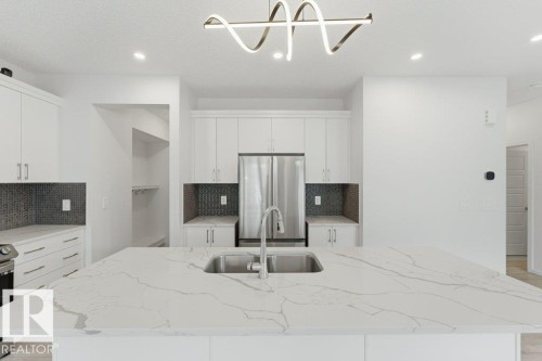 Kitchen island featuring a stainless steel undermount sink, a contemporary faucet, and a light-toned countertop with veining - 2011 207 Street, Edmonton, AB - Indoor Photo Showing Kitchen With Double Sink With Upgraded Kitchen