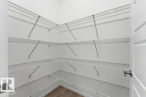 Spacious pantry featuring multiple tiers of wire shelving, white walls, and wood-finish flooring - 2011 207 Street, Edmonton, AB - Indoor With Storage
