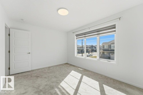 Neutral-toned carpeting and white walls define this room, featuring a large window with roller shades - 2011 207 Street, Edmonton, AB - Indoor Photo Showing Other Room