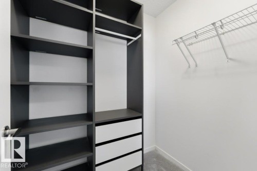 Custom closet system featuring dark wood-finish shelving, built-in drawers, and an integrated hanging rod - 2011 207 Street, Edmonton, AB - Indoor With Storage