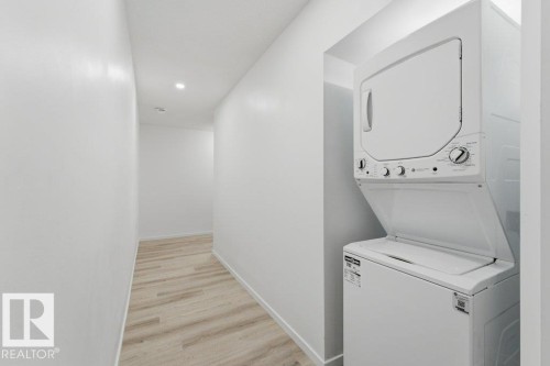 Stackable washer and dryer unit integrated into a hallway alcove featuring recessed lighting and wood-finish flooring - 2011 207 Street, Edmonton, AB - Indoor Photo Showing Laundry Room