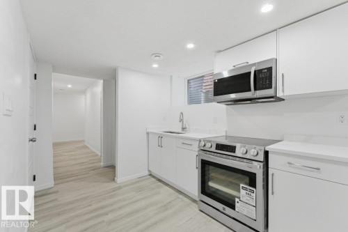 Modern kitchen featuring white cabinetry, light-toned countertops, stainless steel appliances, and recessed lighting - 2011 207 Street, Edmonton, AB - Indoor Photo Showing Kitchen