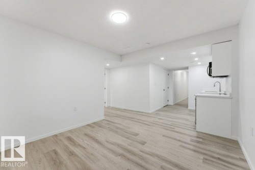Open-concept living area featuring light wood-finish flooring, recessed lighting, and a compact kitchen area - 2011 207 Street, Edmonton, AB - Indoor Photo Showing Other Room
