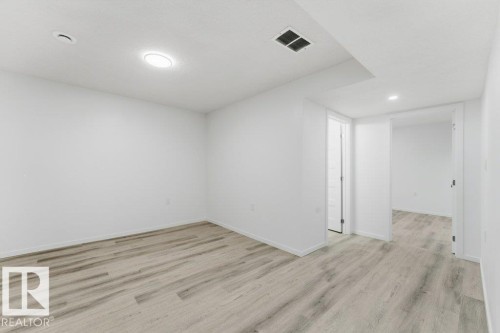 Spacious room featuring light wood-finish flooring, recessed lighting, white walls, and white trim - 2011 207 Street, Edmonton, AB - Indoor Photo Showing Other Room