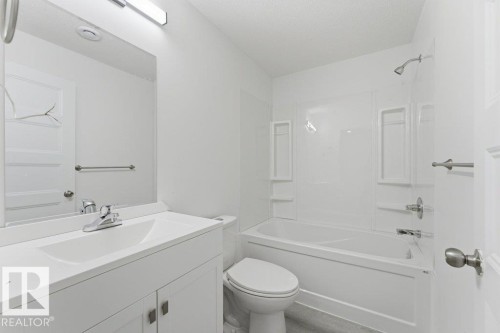 Bathroom featuring a white vanity with an integrated sink, chrome faucet, and a rectangular mirror with an overhead light fixture - 2011 207 Street, Edmonton, AB - Indoor Photo Showing Bathroom