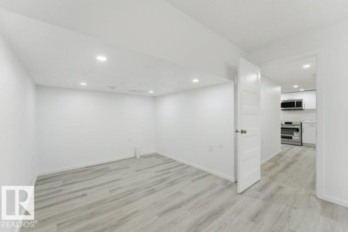 Spacious room featuring light wood-finish flooring, recessed lighting, and a crisp white color palette - 2011 207 Street, Edmonton, AB - Indoor Photo Showing Other Room