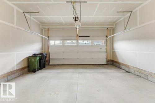 Spacious garage featuring a concrete floor, painted drywall, and an overhead garage door with integrated windows - 2011 207 Street, Edmonton, AB - Indoor Photo Showing Garage