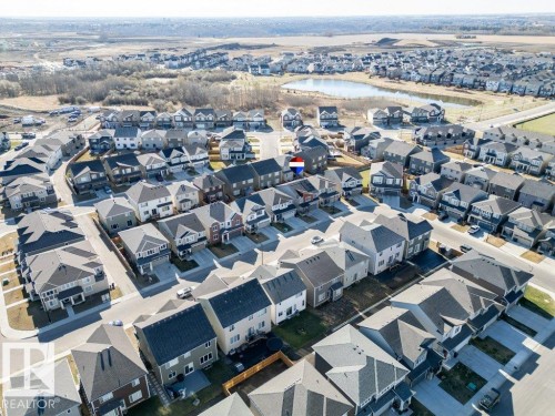 Aerial perspective showcasing a residential development with numerous single-family homes and a central pond - 2011 207 Street, Edmonton, AB - Outdoor With View