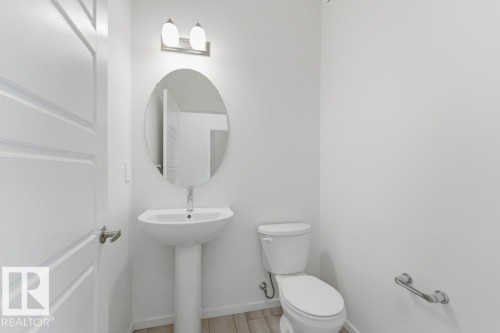 Bathroom featuring a pedestal sink, oval mirror, and wall-mounted light fixture - 2011 207 Street, Edmonton, AB - Indoor Photo Showing Bathroom