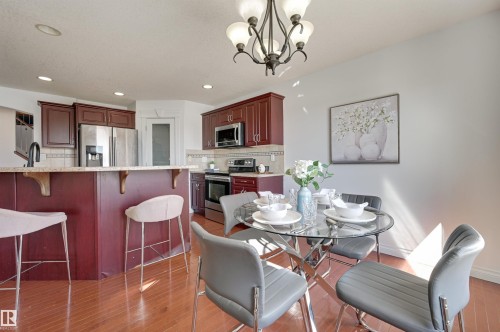 The kitchen features dark wood cabinetry, stainless steel appliances, and a tiled backsplash - 24 Birchmont Drive, Leduc, AB - Indoor Photo Showing Dining Room